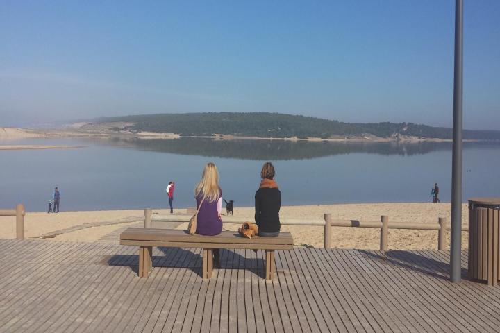 a person sitting on a bench next to a body of water