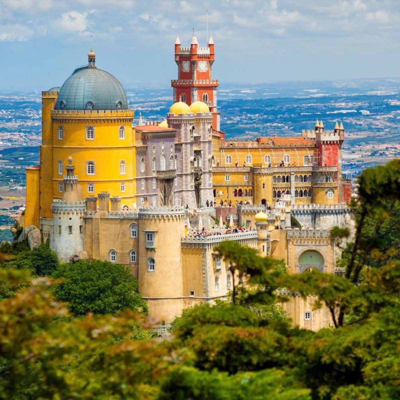 a castle with a clock tower next to a body of water