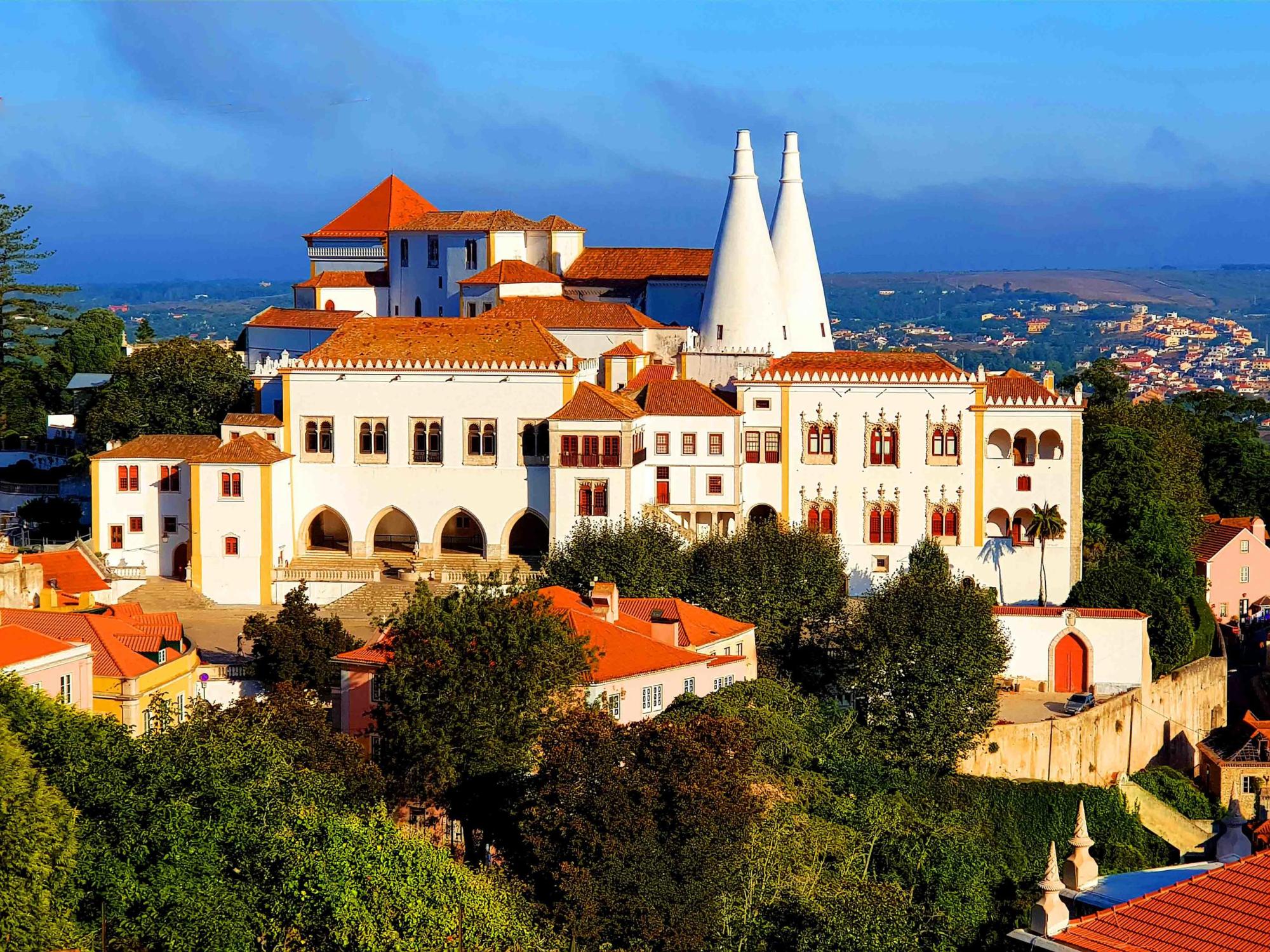 a group of people standing in front of a castle with Sintra in the background