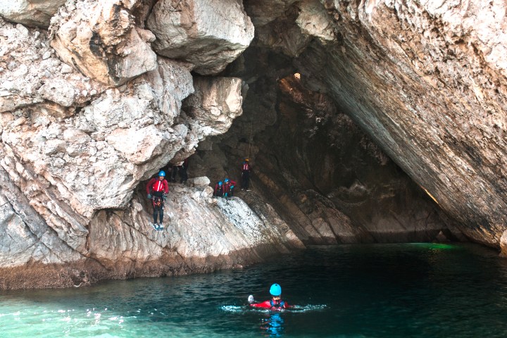 a person swimming in water next to the rock
