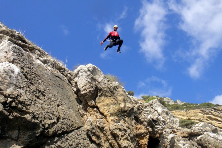 a man flying through the air on a rocky hill