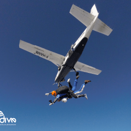 Two skydivers jumping from a small plane in clear blue sky.