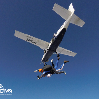 Two skydivers jumping from a small plane in clear blue sky.